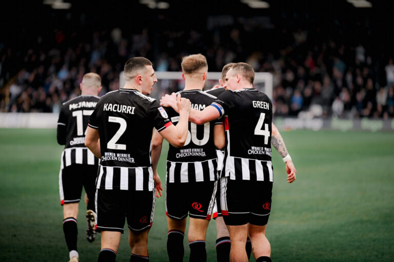 GTFC players celebrating on the pitch showing their Winner Winner Chicken Dinner back logo